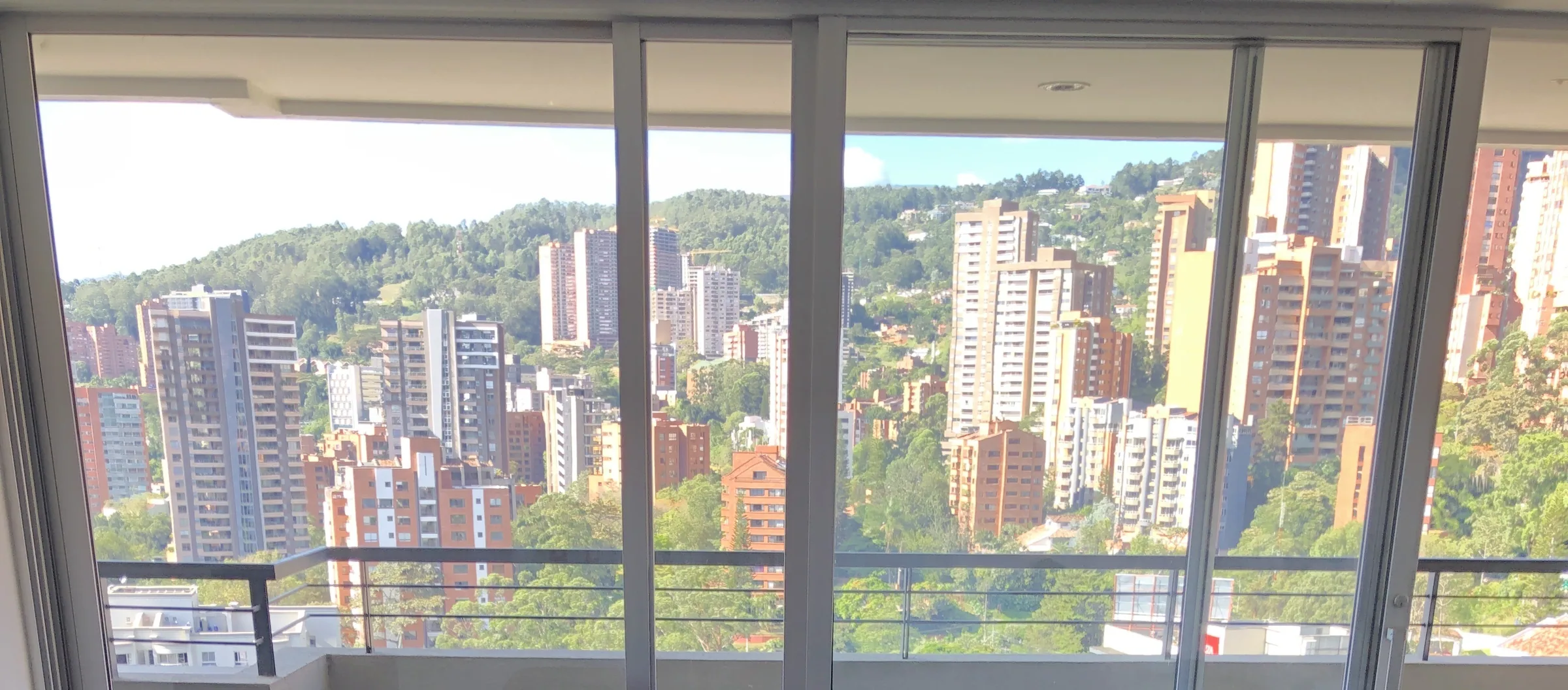 Panoramic view from the apartment across El Poblado's residential towers to forested hillsides